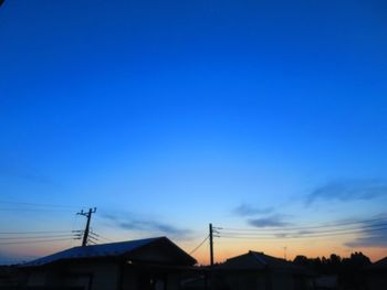 Low angle view of silhouette buildings against blue sky