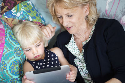 Grandmother with granddaughter using digital tablet