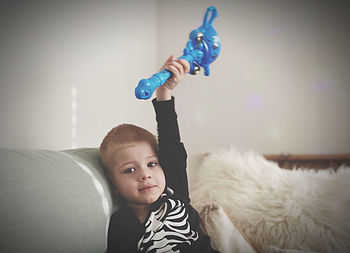 Portrait of boy holding toy at home