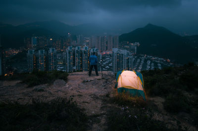Man traveler taking photo on top of mountains near of tent camping