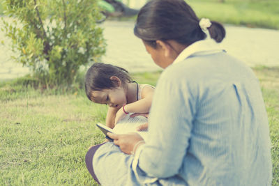 Side view of boy sitting on field