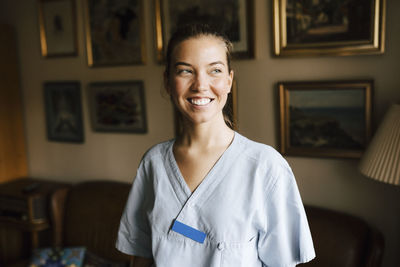 Happy female nurse looking away in living room