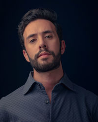 Portrait of young man against black background