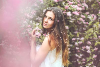 Portrait of beautiful woman standing by pink flower