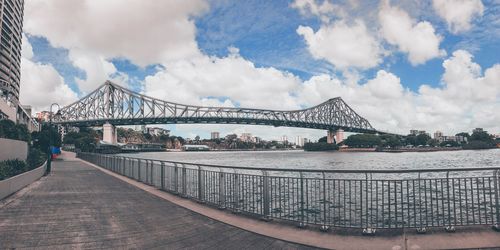 Bridge over river against cloudy sky