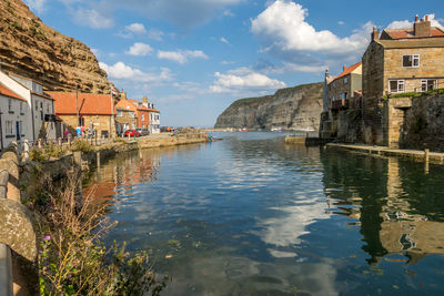 Buildings by lake against sky in city