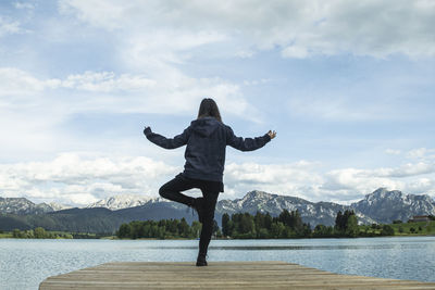 Woman at a pier at a lake raising her arms 