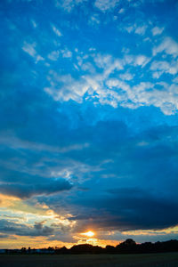 Low angle view of dramatic sky over silhouette landscape