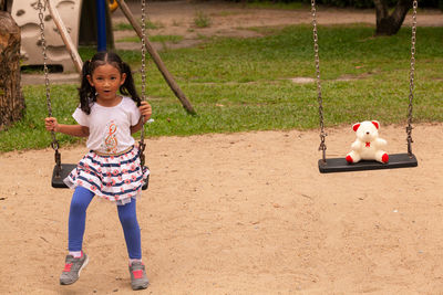 Full length of a smiling girl on swing at playground