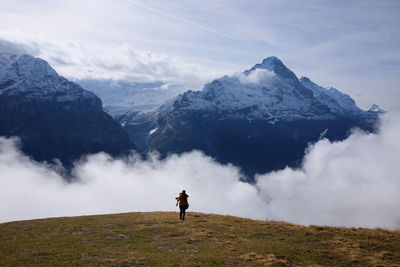 Rear view of woman standing on mountain against sky