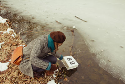 High angle view of woman with number 89 on block at frozen riverbank