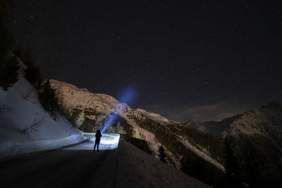 Person standing on mountain against sky at night