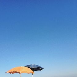 Orange and blue parasols against clear sky