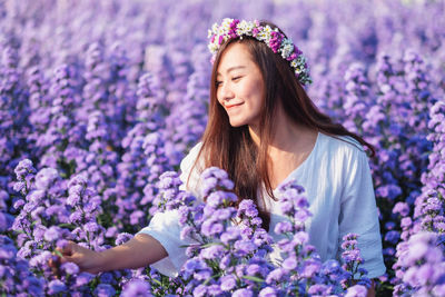 Beautiful woman wearing tiara looking at flowers