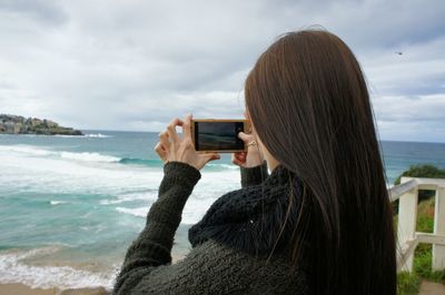 Rear view of woman photographing sea