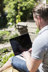 Side view of man using laptop on terrace