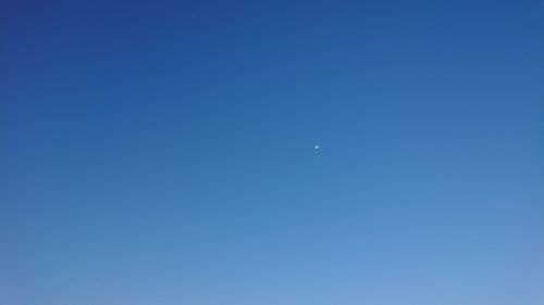 Low angle view of moon against clear blue sky