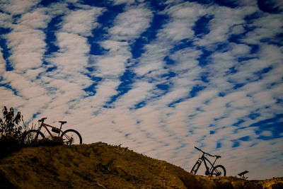 Low angle view of bicycle against cloudy sky