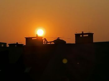 Silhouette house against orange sky during sunset