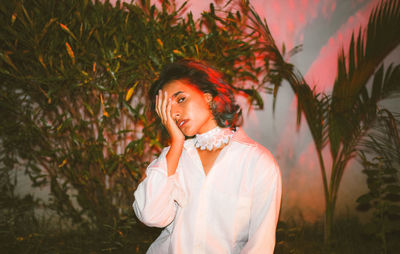 Portrait of beautiful young woman standing against plants