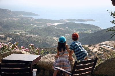 Rear view of friends standing on mountain against sky