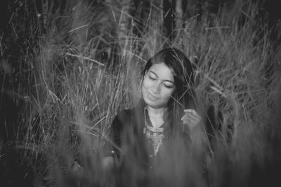 Young woman sitting amidst grass on field