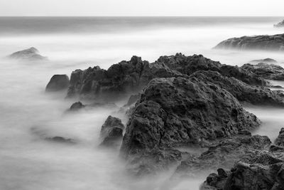 Scenic view of rocks in sea against sky