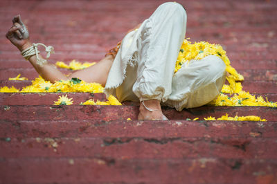 Low angle view of man lying with yellow flowers on steps