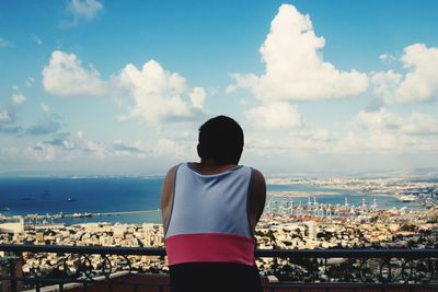 Rear view of man standing by sea against sky