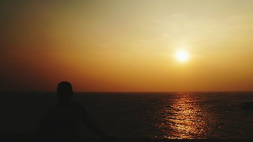 Silhouette man standing on beach against sky during sunset