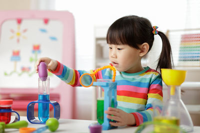 Cute girl playing with scientific toys at home