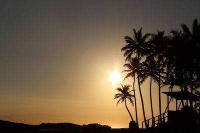 Silhouette palm trees on beach against clear sky at sunset