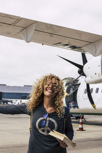 Portrait of smiling young woman standing against sky