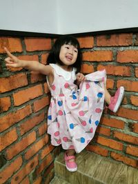 Girl standing by brick wall