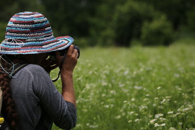 Rear view of woman photographing on field