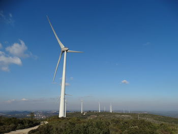 Windmill on landscape against blue sky