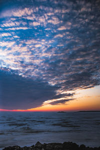 Scenic view of sea against dramatic sky during sunset