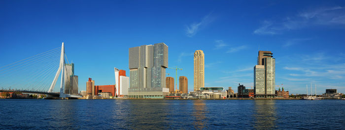 City by river and buildings against blue sky