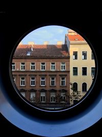 Buildings against sky seen through window