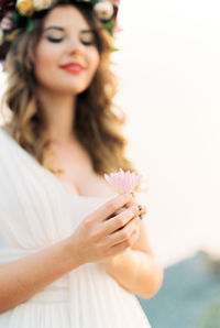 Portrait of young woman holding gift against white background