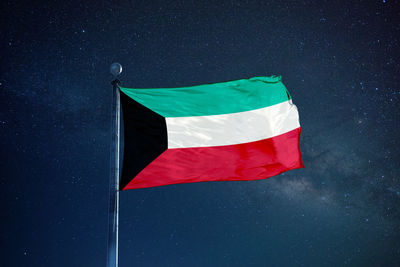 Low angle view of kuwaiti flag against star field sky