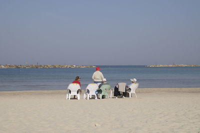 People sitting on chairs at beach