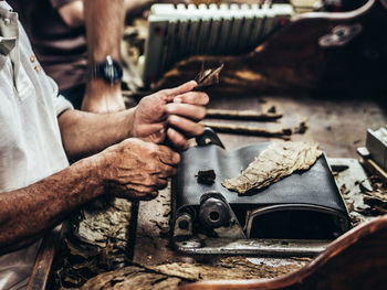 Close-up of manual worker making cigar in factory