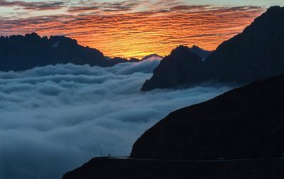Silhouette mountain by sea against sky during sunset