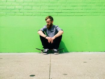 Man sitting in front of green wall