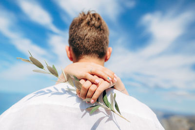 Rear view of man with arms raised against sky