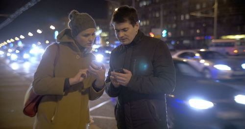 Young couple holding illuminated lights at night