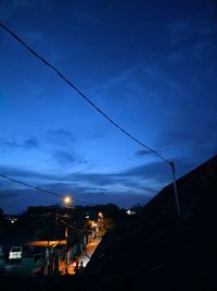 Illuminated street amidst buildings against sky at dusk