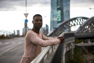 Man standing on bridge in city against sky