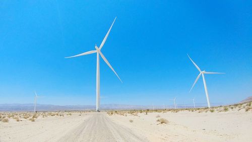 Wind turbines on land against clear blue sky